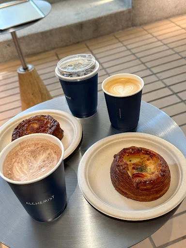 Coffee and croissants at Alchemist The Heeren Singapore, including iced latte and baked pastries.
