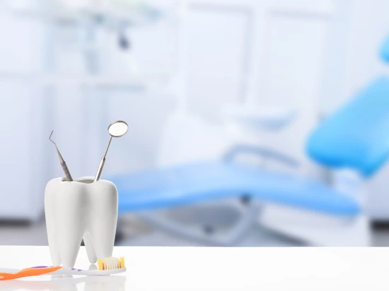 Dental tools in a tooth-like holder with a toothbrush nearby in a dental clinic.