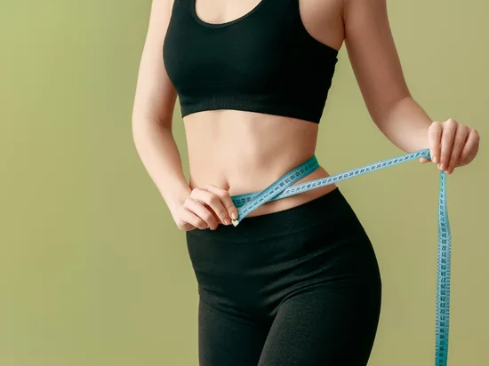 Woman measuring waist to show weight loss benefits of Tirzepatide for obesity treatment.