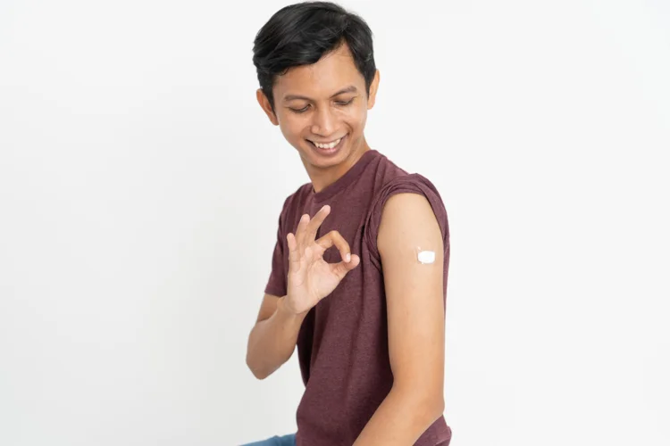 Asian man feeling confident after receiving his Tdap booster vaccine to protect against Tetanus, Diphtheria, and Pertussis.