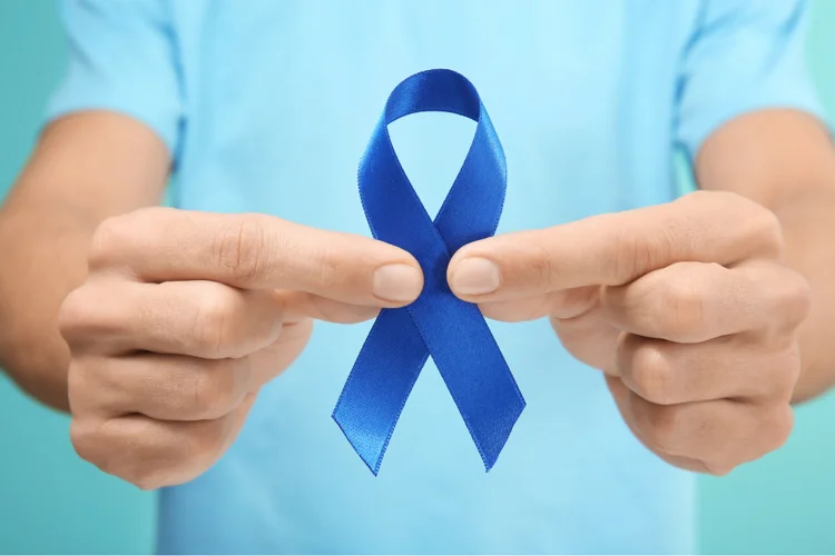 Asian man holding a blue ribbon in support of prostate cancer awareness and early detection for timely intervention.