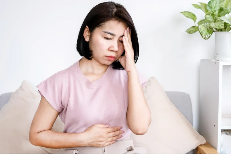Asian woman feeling dizzy due to high or fluctuating blood pressure.