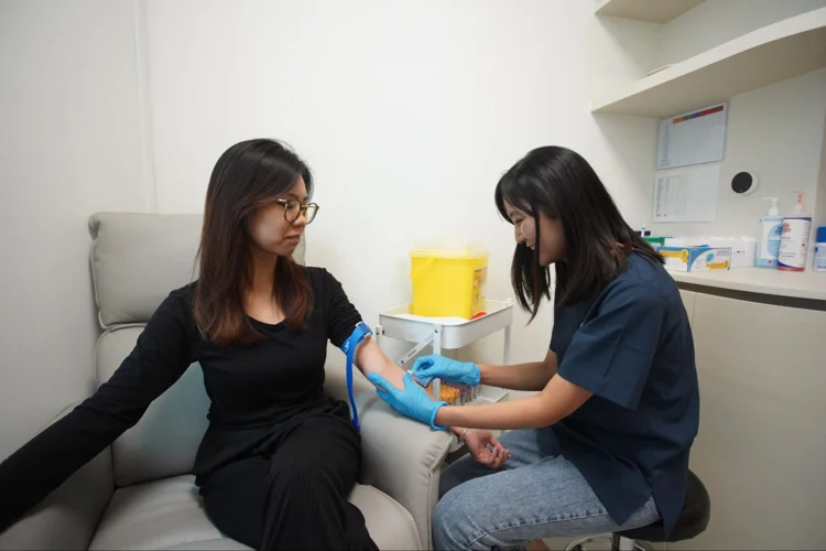 Asian woman providing blood sample for Liquid Biopsy.