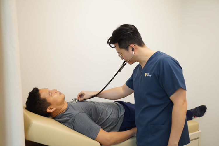 ATA doctor physically examining an Asian man as part of a health screening package for a comprehensive analysis of health.