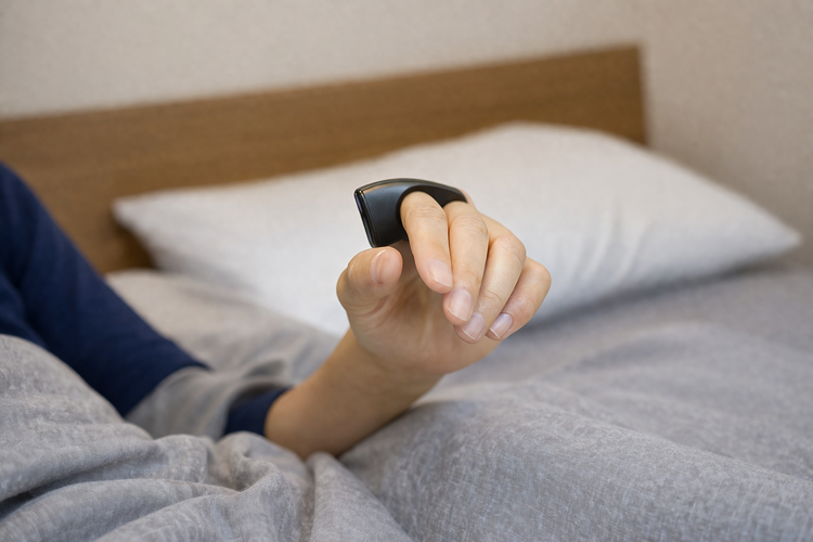 Patient on the bed wearing the Belun Ring on their finger for a home sleep test.