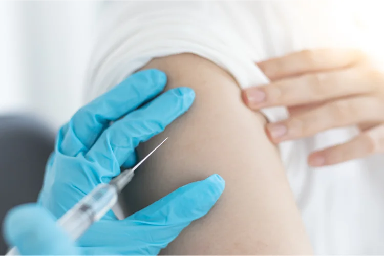 Close-up of a doctor administering a polio vaccine injection to a Singaporean adult’s upper arm.