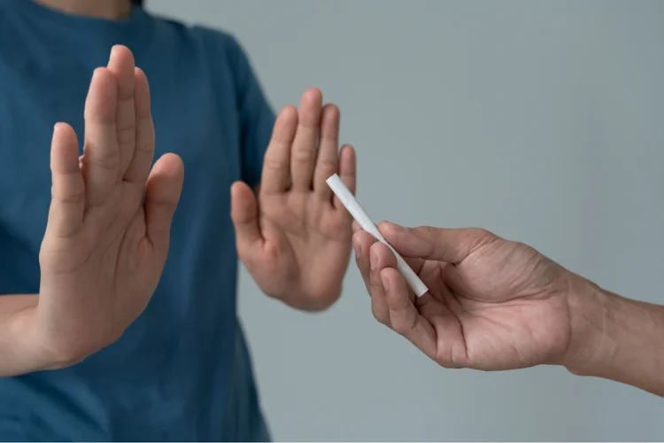 Close-up of a person refusing a cigarette offer, illustrating asthma management by avoiding smoking and related triggers.