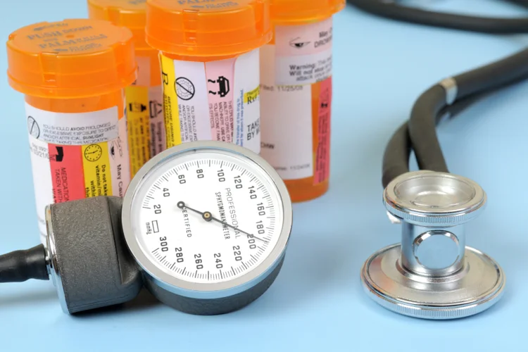 Close-up of a blood pressure gauge with an orange prescription bottle and a stethoscope, representing high blood pressure medication and treatment options.