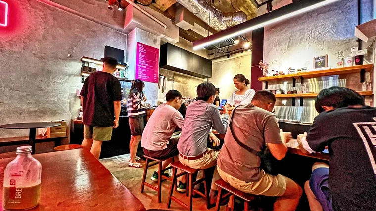 Cozy modern interior of The Community Coffee in Far East Plaza with customers enjoying drinks.