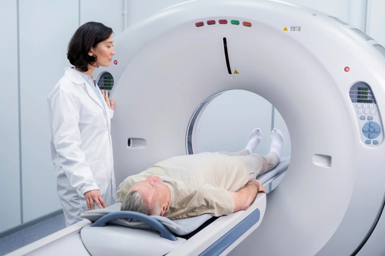 Patient undergoing CT scan at clinic with radiologist operating the CT scanner.