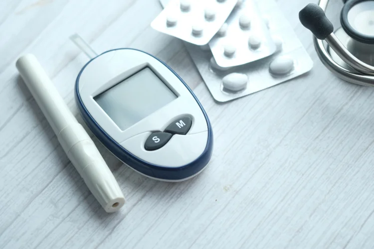 Diabetes monitoring kit, including a glucometer, insulin pen, and medication, placed on a white table — essential tools for blood sugar control.