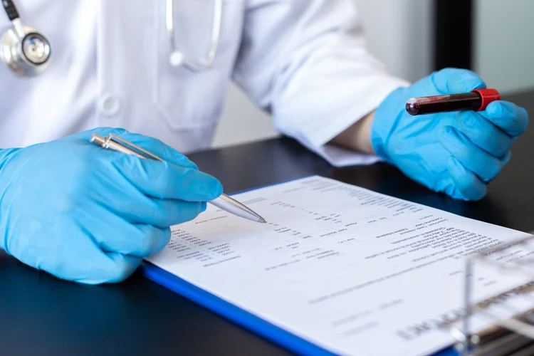 Doctor wearing gloves reviewing Mumps IgG blood test results on clipboard in clinic environment.