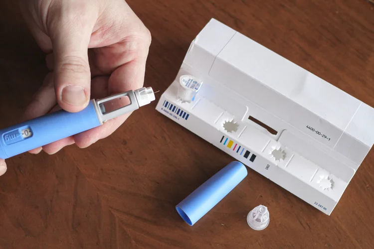 Hand holding Liraglutide injection pen on table for weight management treatment.