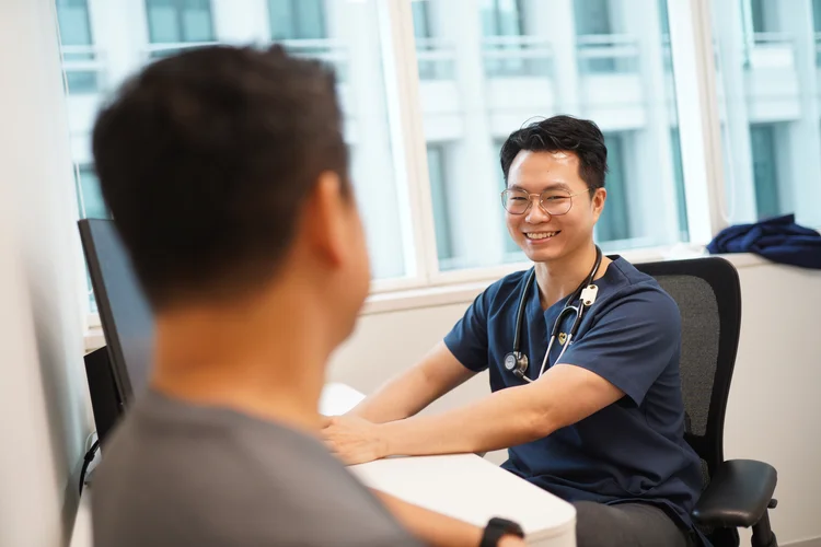Male doctor smiling during consultation to explain purpose and benefits of men’s health screening.