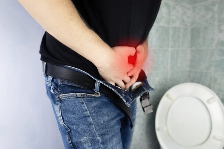 Man holding lower abdomen in discomfort showing painful genital symptoms of chancroid infection.