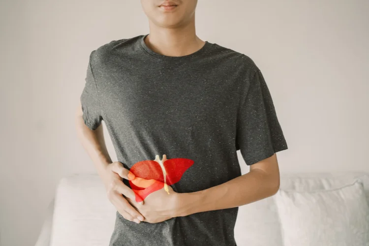 Man clutching upper right abdomen in discomfort, suggesting symptoms of chronic Hepatitis B.