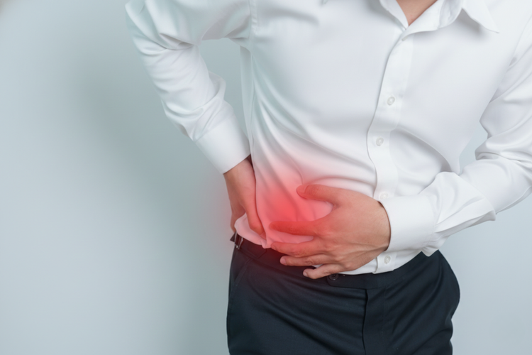 Man clutching right abdomen with discomfort, a symptom of fatty liver disease.