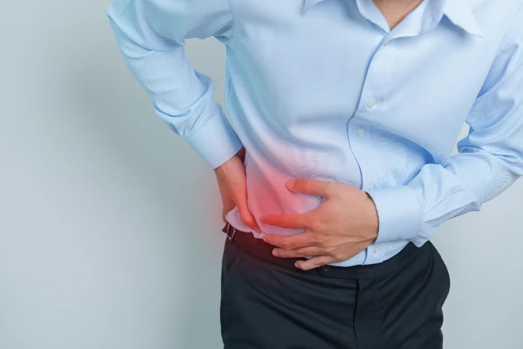 Man holding right side in pain, suggesting liver discomfort from possible fatty liver.