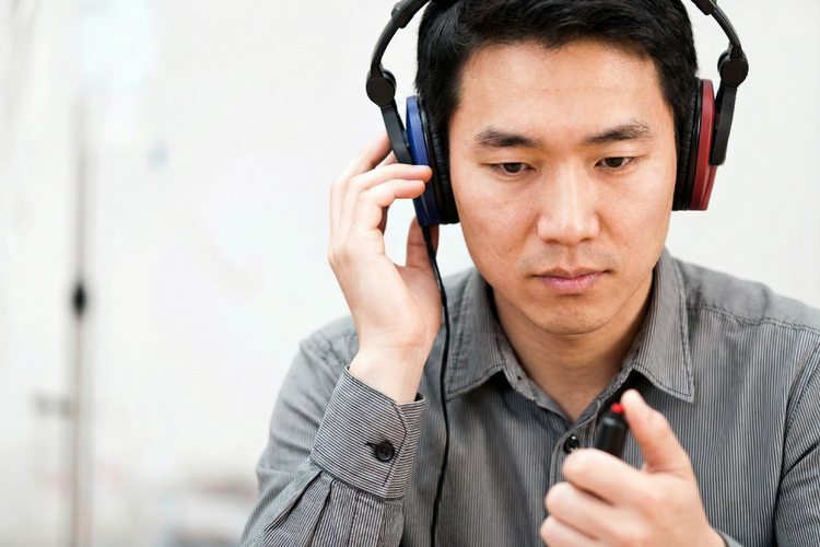Man using headphones during audiometry test while indicating responses for hearing assessment.