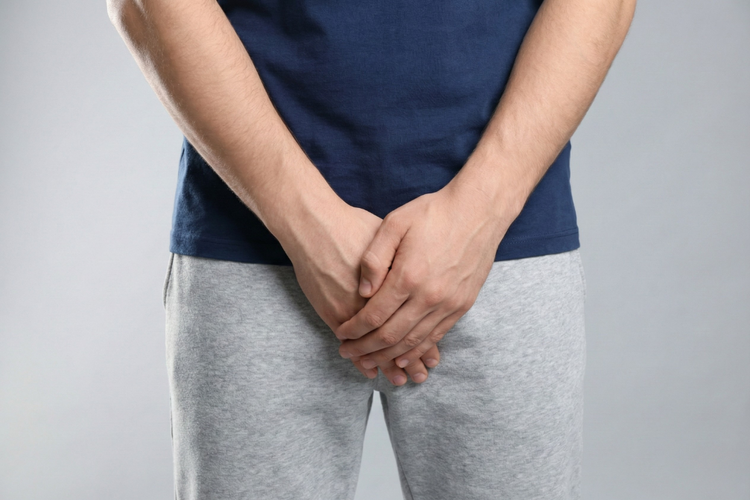 Man covering groin area due to discomfort from possible STD symptoms.