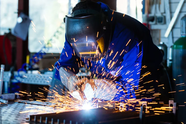 Metalworker using welding equipment with sparks flying, representing occupational exposure to aluminium in industrial settings.