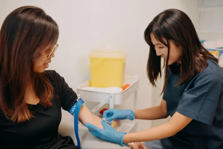 Nurse drawing blood from female patient for thyroid function test.