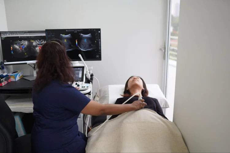 Female radiologist using ultrasound scan machine to scan patient's abdomen area.