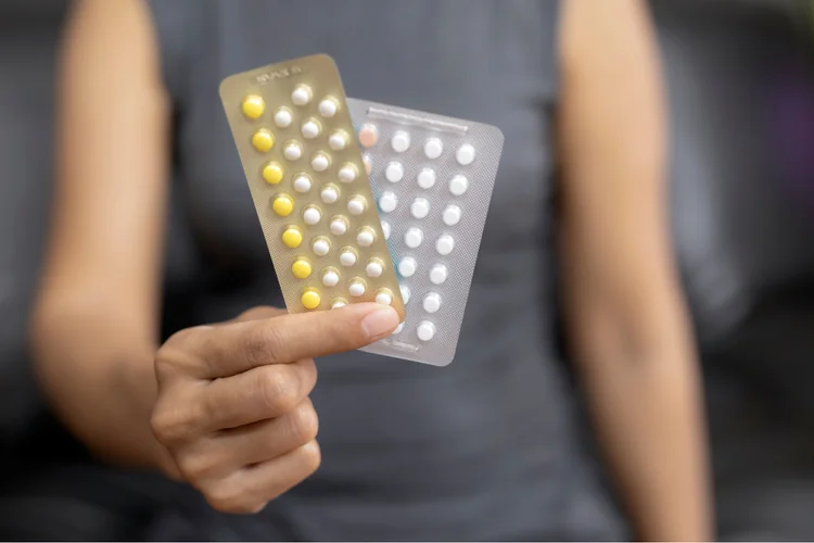Woman holding different types of birth control pills including combined and progestin-only options.