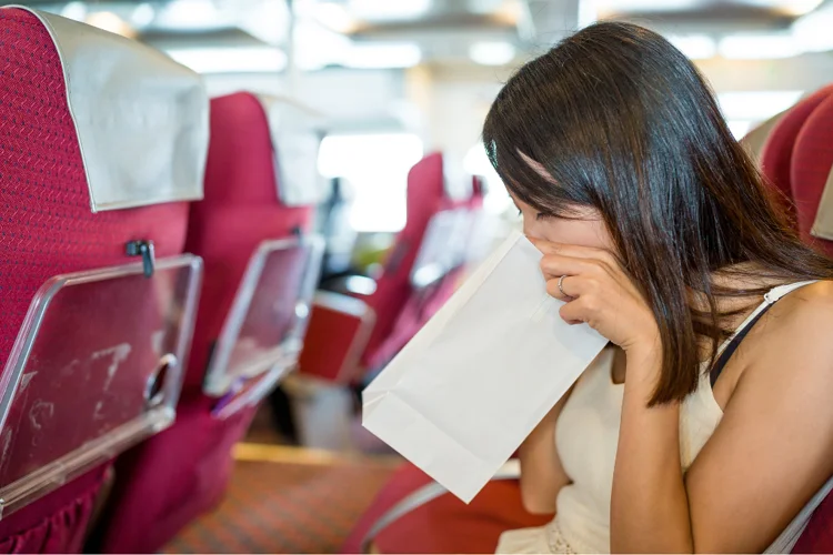 Woman on a boat using a sickness bag to manage motion sickness symptoms such as nausea and vomiting.