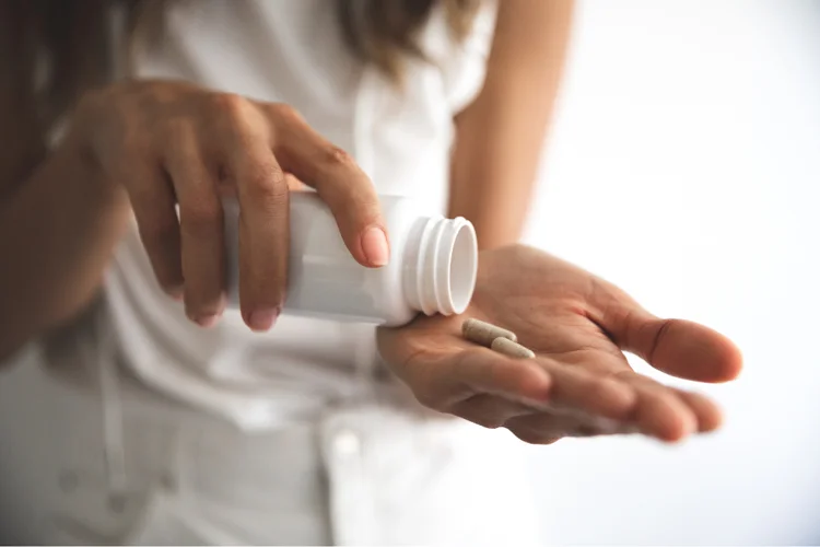 Woman taking iron supplements to replenish iron levels in her body for moderate to severe deficiency.