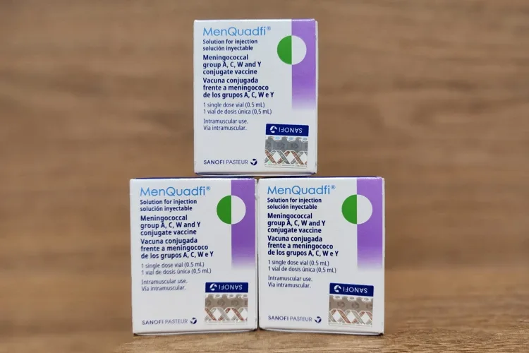 叠放在木桌上的三盒 MenQuadfi 脑膜炎球菌 ACWY 疫苗